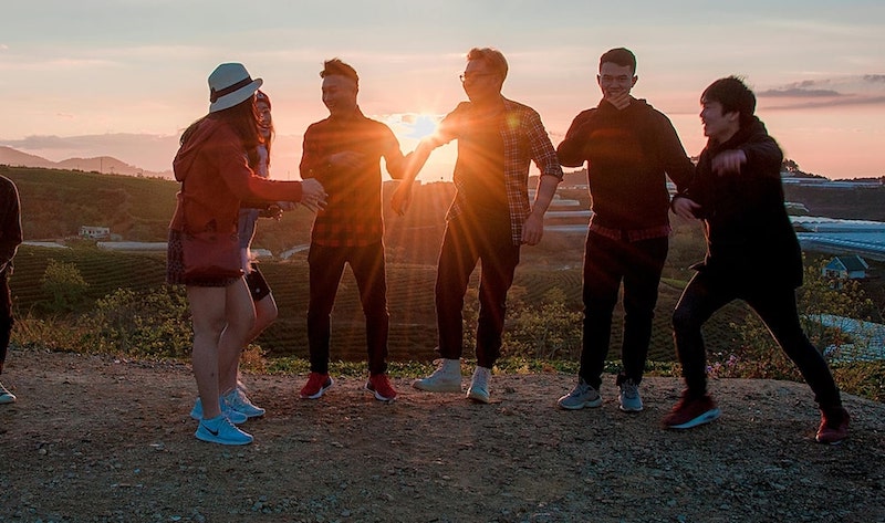 teens on hill top together smiling in setting sun