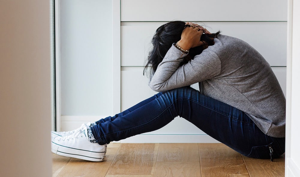 teenager sat on floor with head in hands