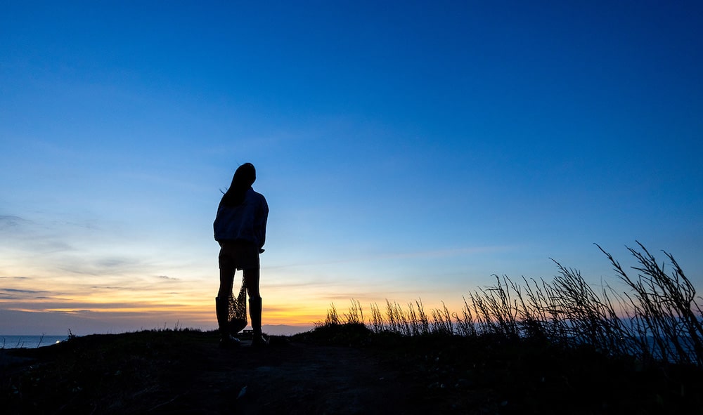 person by ocean silhouetted at sunset